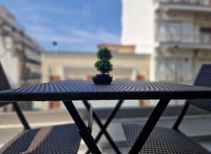 A metal table with a small potted plant on it, surrounded by wicker chairs. - Volos Terra Deluxe Residences (Volos)