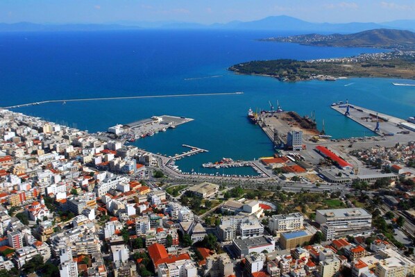 An aerial view of a coastal city with a marina, dense urban area, and a clear view of the sea.