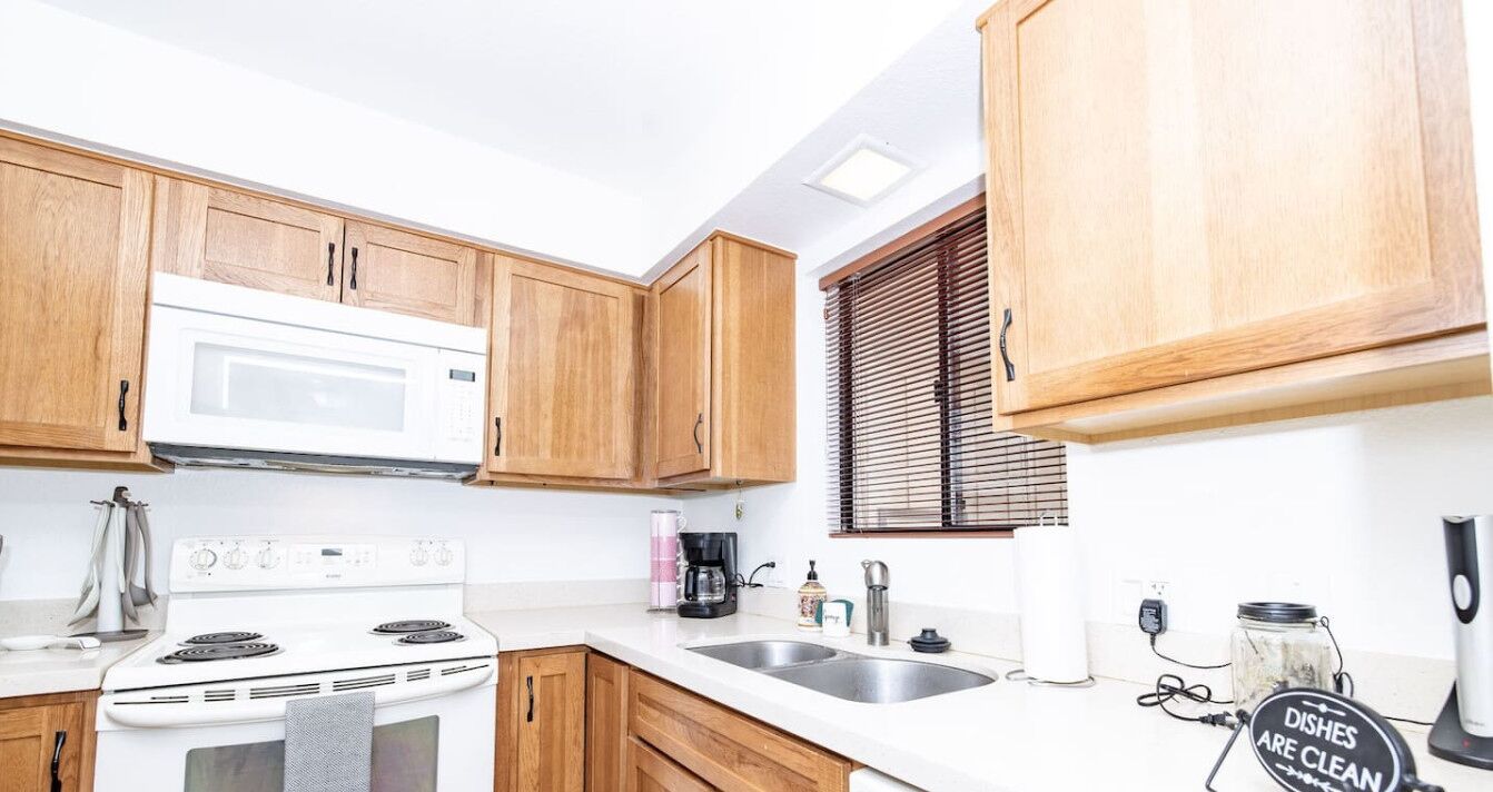 Une cuisine avec des meubles de rangement en bois, une cuisinière blanche, un évier et une machine à café.