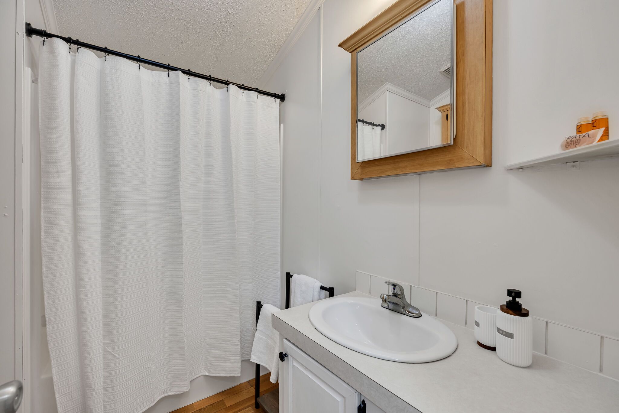 A bathroom with a white sink, mirror, and shower curtain.