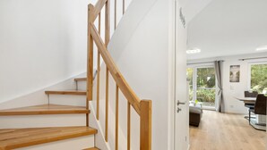 A modern interior with a wooden staircase, a dining area, and a view through glass doors. - Cozy home in Tossens with sauna (Tossens)