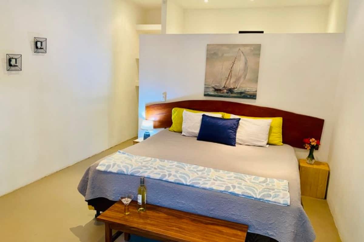 A neatly arranged bedroom with a bed, bedside table, and a painting on the wall.