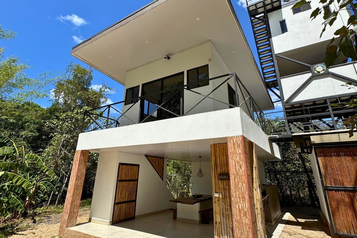 A modern two-story building with a flat roof, large windows, and a balcony.