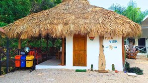 A small building with a thatched roof, a wooden door, and a sign reading "PURA VIDA". - Antema Lodge (Tamarindo)