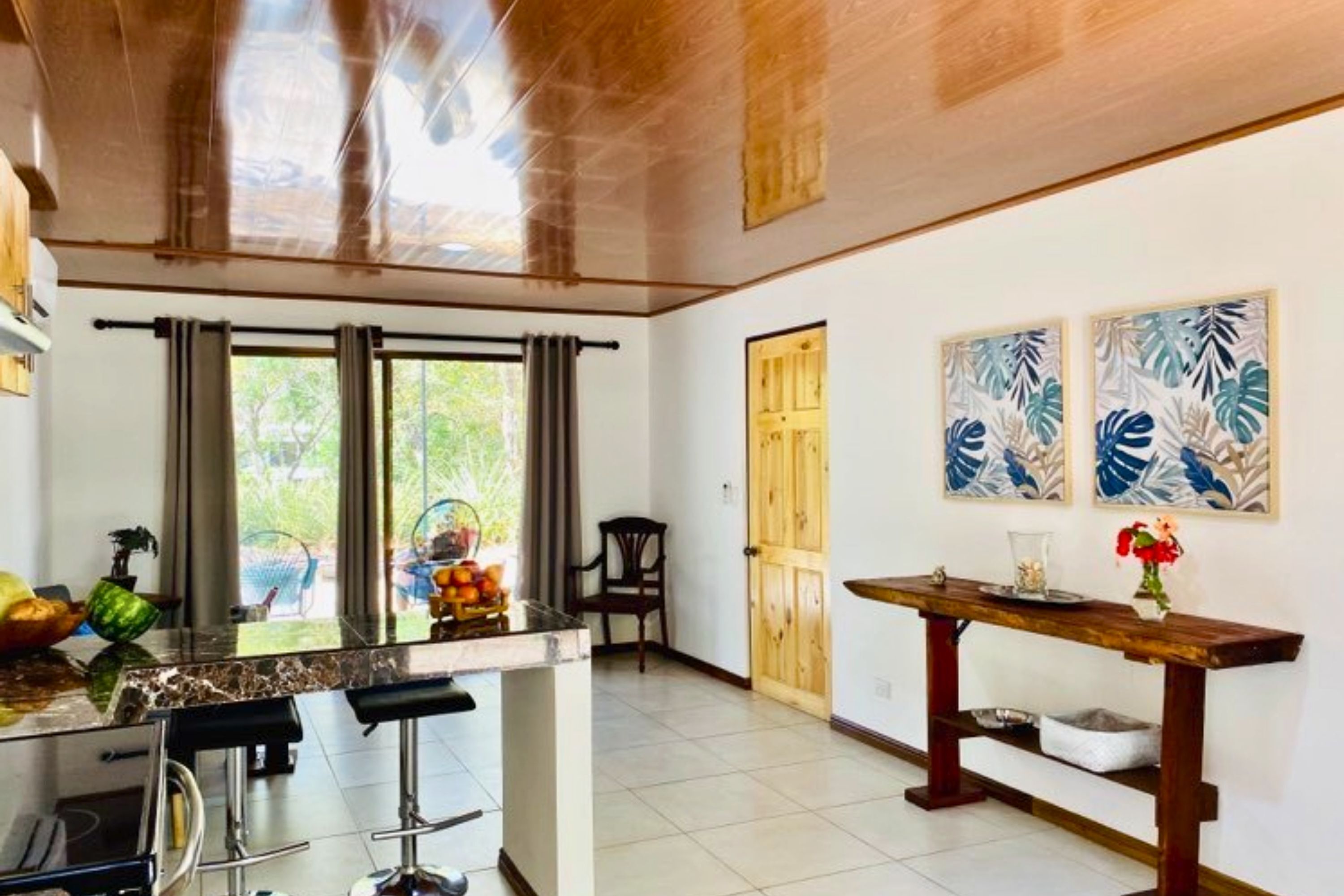 A kitchen with a bar area, a wooden door, and two wall-mounted artworks.