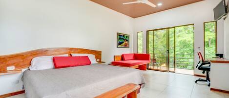 A modern bedroom with a large bed, a wooden bench, a desk, and a red sofa.