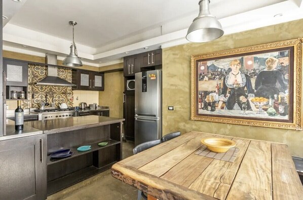 A modern kitchen with a central island, stainless steel appliances, and a dining table.