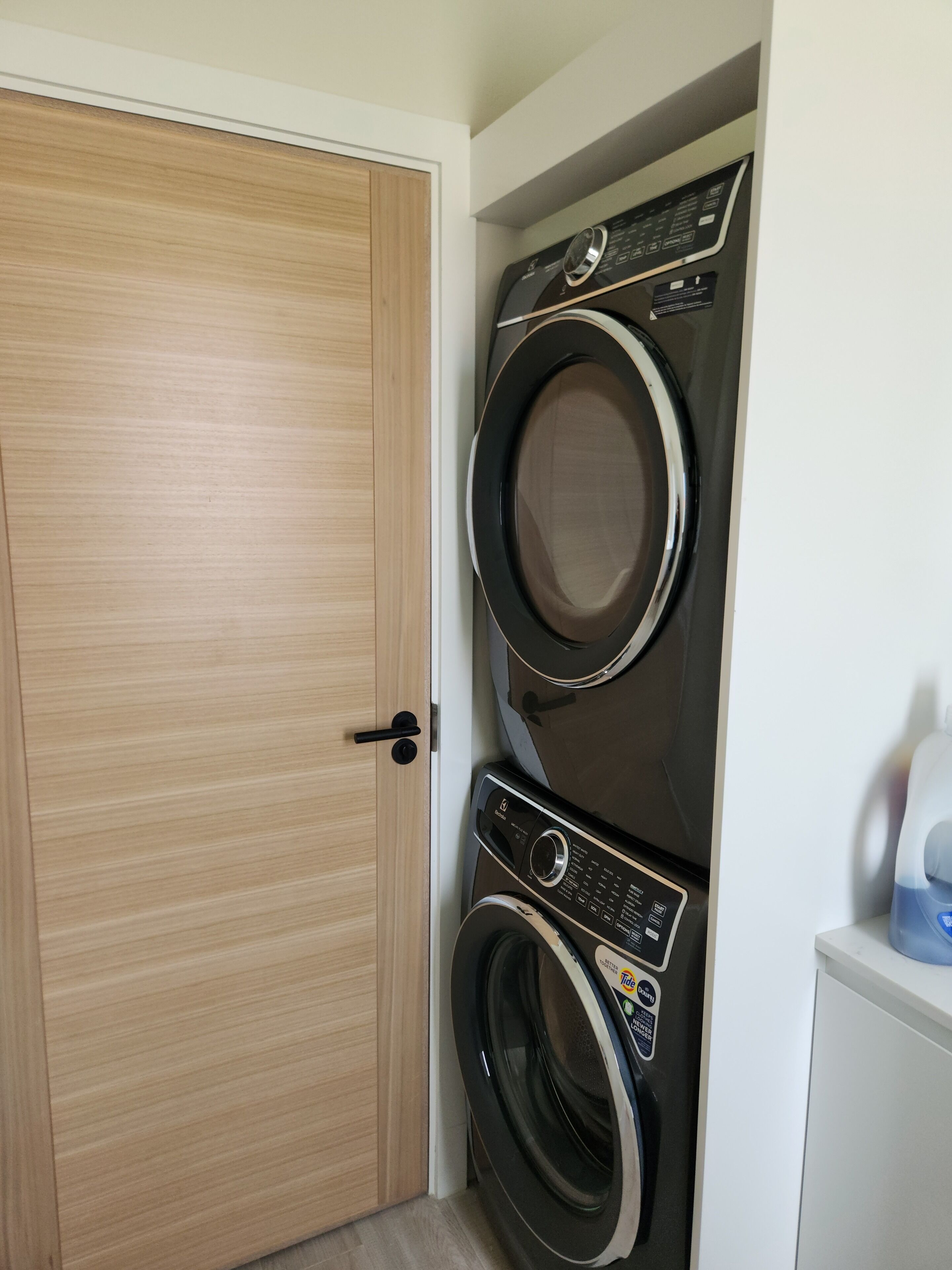 A laundry room with a wooden door and two stacked washing machines.