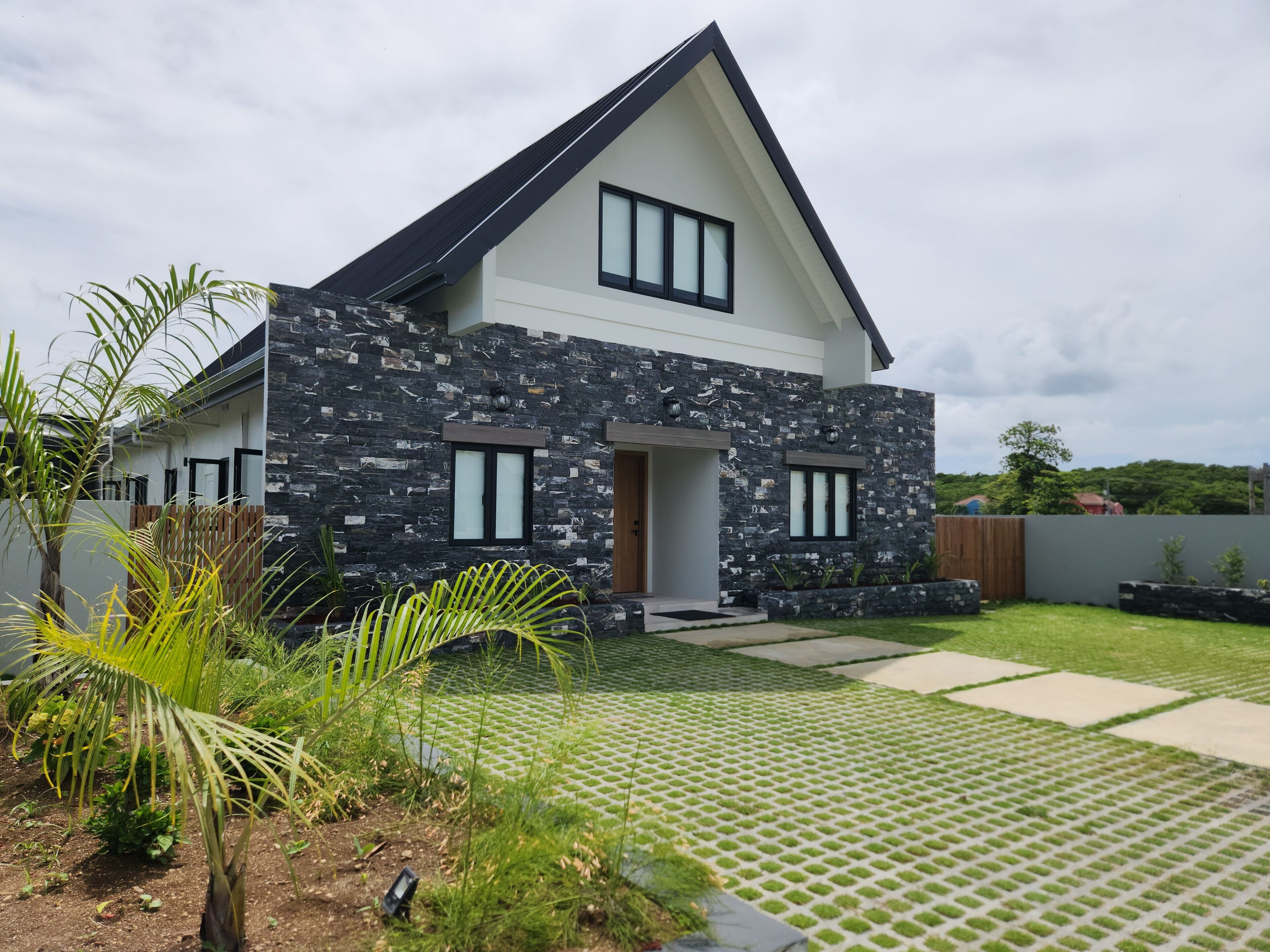 A modern two-story house with a stone facade, a sloped roof, and a front door.
