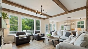 A spacious living room with a fireplace, large windows, and a high ceiling with exposed beams. - NEW Luxury Cottage with Mountain Views (Stanley)