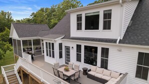 A two-story house with a covered patio area featuring a dining table and outdoor seating. - NEW Luxury Cottage with Mountain Views (Stanley)