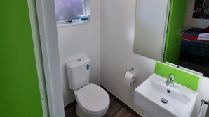A small, modern bathroom with a toilet, sink, and window. - Stay Timaru (Timaru)
