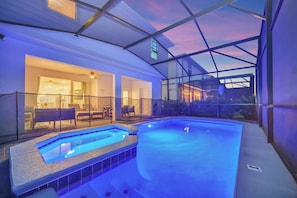 Ein moderner, überdachter Pool mit Glaswänden, ein separater Whirlpool und eine Terrasse mit Sitzgelegenheiten.