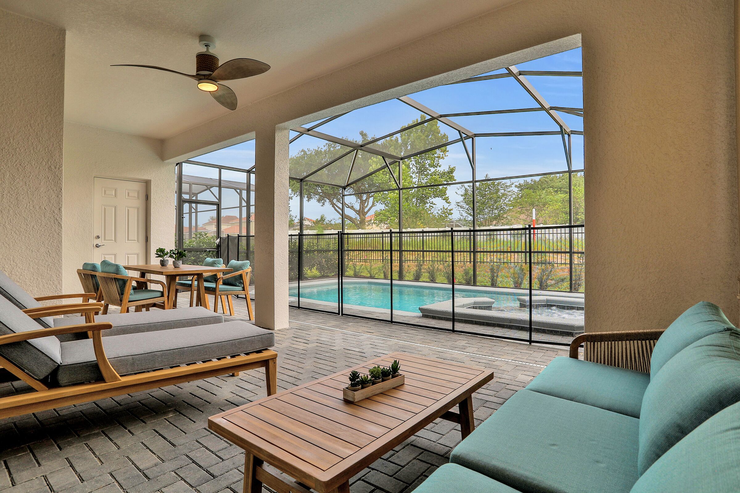 Eine überdachte Terrasse mit Pool, Gartenmöbeln und Deckenventilator.