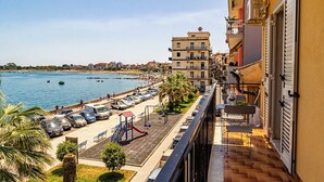 Un balcón con vista a una playa y coches aparcados.