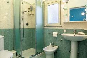 Ein Badezimmer mit einer Duschkabine, einem Standwaschbecken und einem Bidet.