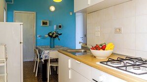 Una cocina con pared azul, armarios blancos, encimera de madera, estufa a gas y un fregadero.