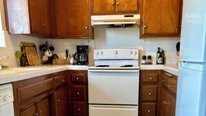 Une cuisine avec des meubles de rangement en bois, une cuisinière blanche et un réfrigérateur.