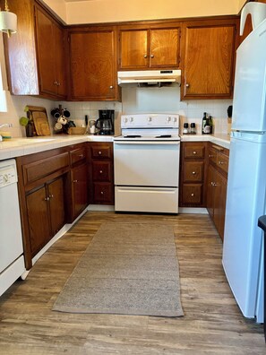 A kitchen with wooden cabinets, a white stove, and a refrigerator. - Comfy Retreat Near Beach & Downtown Long Beach (Long Beach)