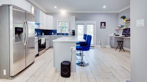 A modern kitchen with stainless steel appliances, a central island, and a blue bar stool.