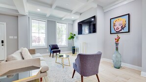 A modern living room with a sofa, armchairs, a coffee table, and a large window.