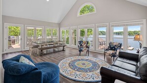 A spacious room with a dining area, a large window overlooking a lake, and a cozy seating area with a patterned rug. - Keepin' It Cooley by SoCharm | Lake Norman! (Mooresville)