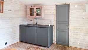Una cocina compacta con encimera gris oscuro, un mueble de madera y una puerta gris.