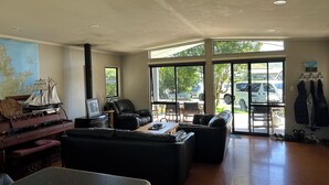 Un amplio salón con un ventanal grande, un mapa en la pared, un piano y una chimenea.