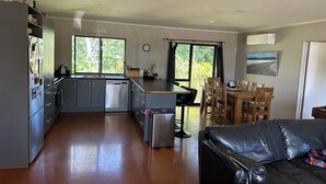 Una cocina compacta con lavavajillas, un comedor con mesa y sillas de madera, y un sofá de cuero negro.