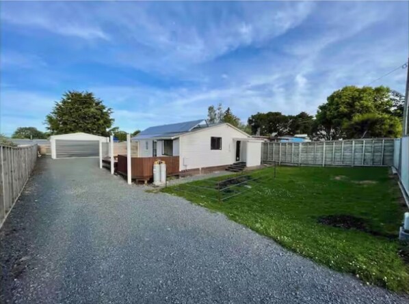 A single-story house with a gravel driveway, a small front yard, and a garage.