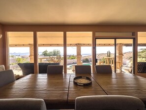 Enjoy meals with a view of the desert landscape from this dining area, featuring a large table and four chairs.