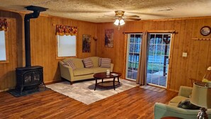 A cozy living room with wooden walls, a sofa, a coffee table, and a fireplace. - Cozy Bear Rock Cottage with hot tub  (Monroe)