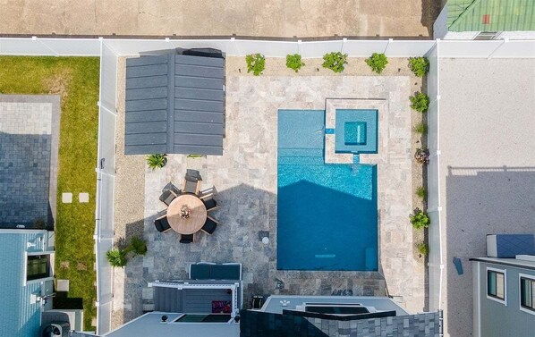 Eine Vogelperspektive zeigt eine Dachterrasse mit Swimmingpool, einer überdachten Sitzgelegenheit und einem kleinen Garten.