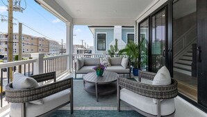 Un balcon agrémenté de meubles en osier, d’une table ronde et de plantes en pot.
