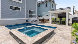 Un jardin à l’arrière d’une maison, avec une piscine, un espace salon extérieur et une terrasse couverte.