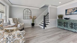 Un salon spacieux, agrémenté de meubles à motifs, d’un escalier et d’une vitrine décorative.