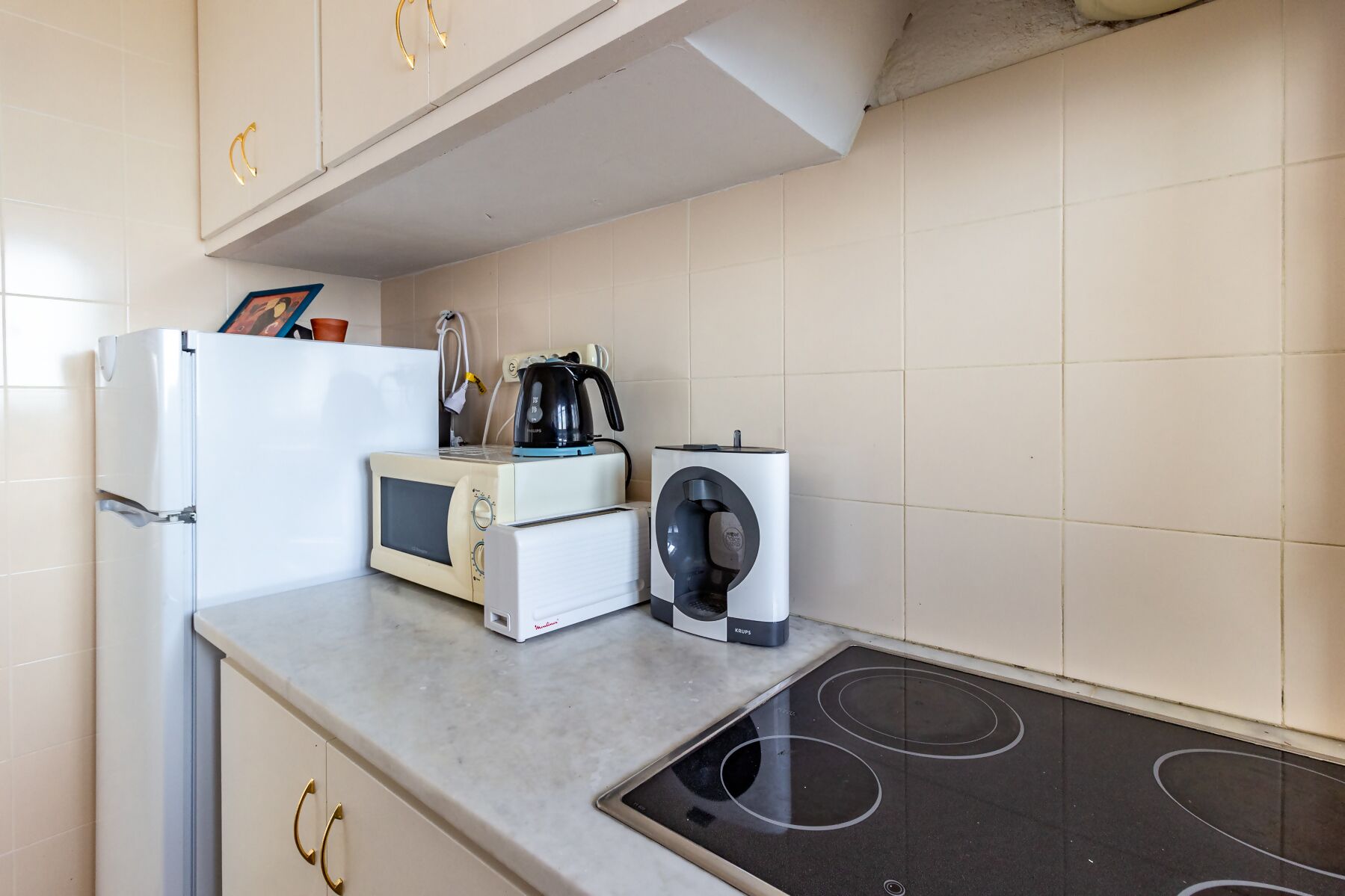 A kitchen with a built-in microwave, a coffee maker, and a Krups electric kettle.