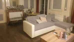 Una sala de estar con un sofá gris, una mesa de centro de madera y una mesita con adornos.