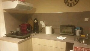 Cocina compacta con estufa, reloj, tostadora y lavabo.