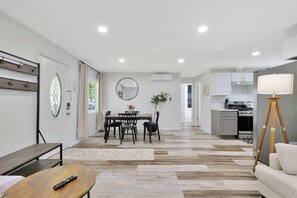 Ein modernes Wohnzimmer mit Essbereich, einer Küche und einer Treppe zu einer oberen Etage.