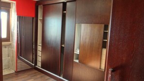 Una habitación con un armario de madera corredero, una pared roja y un ventanal.