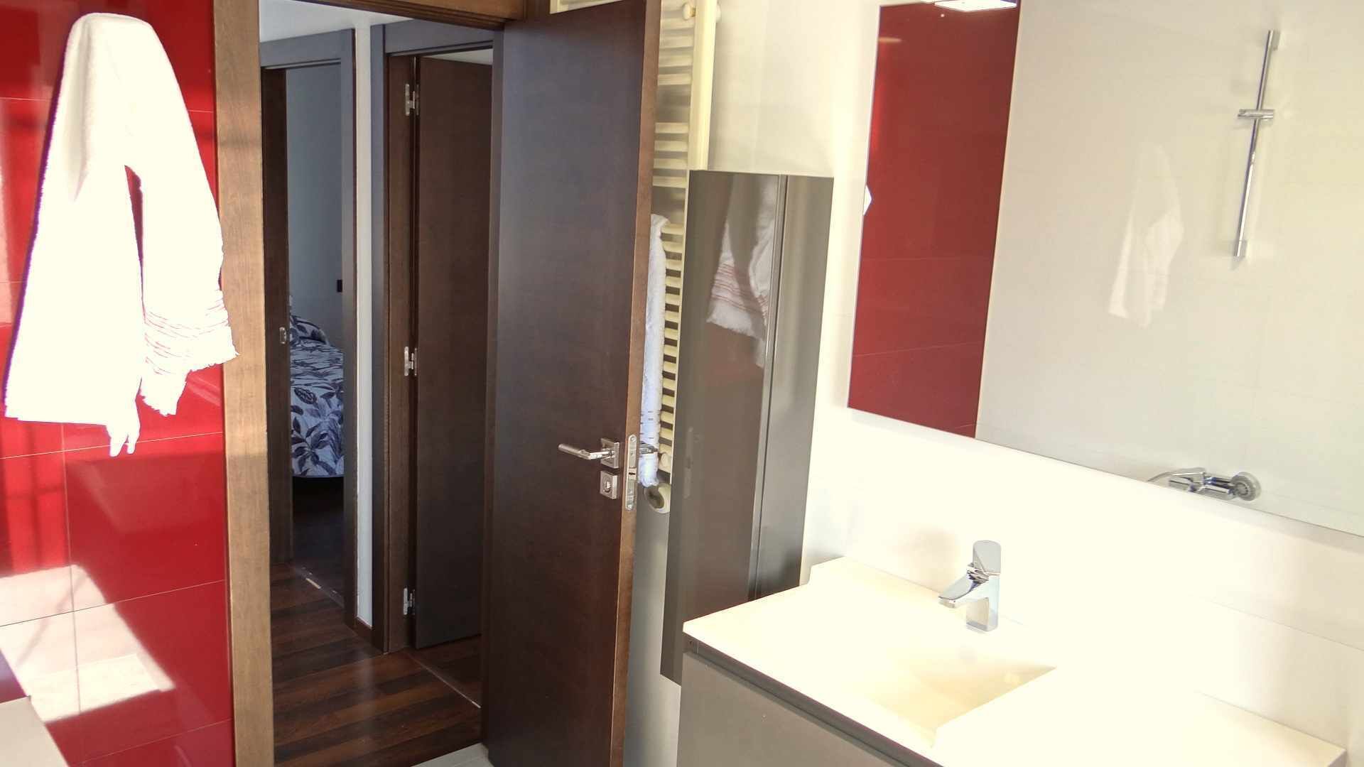 A modern bathroom with a large mirror, a sink, and a shower.