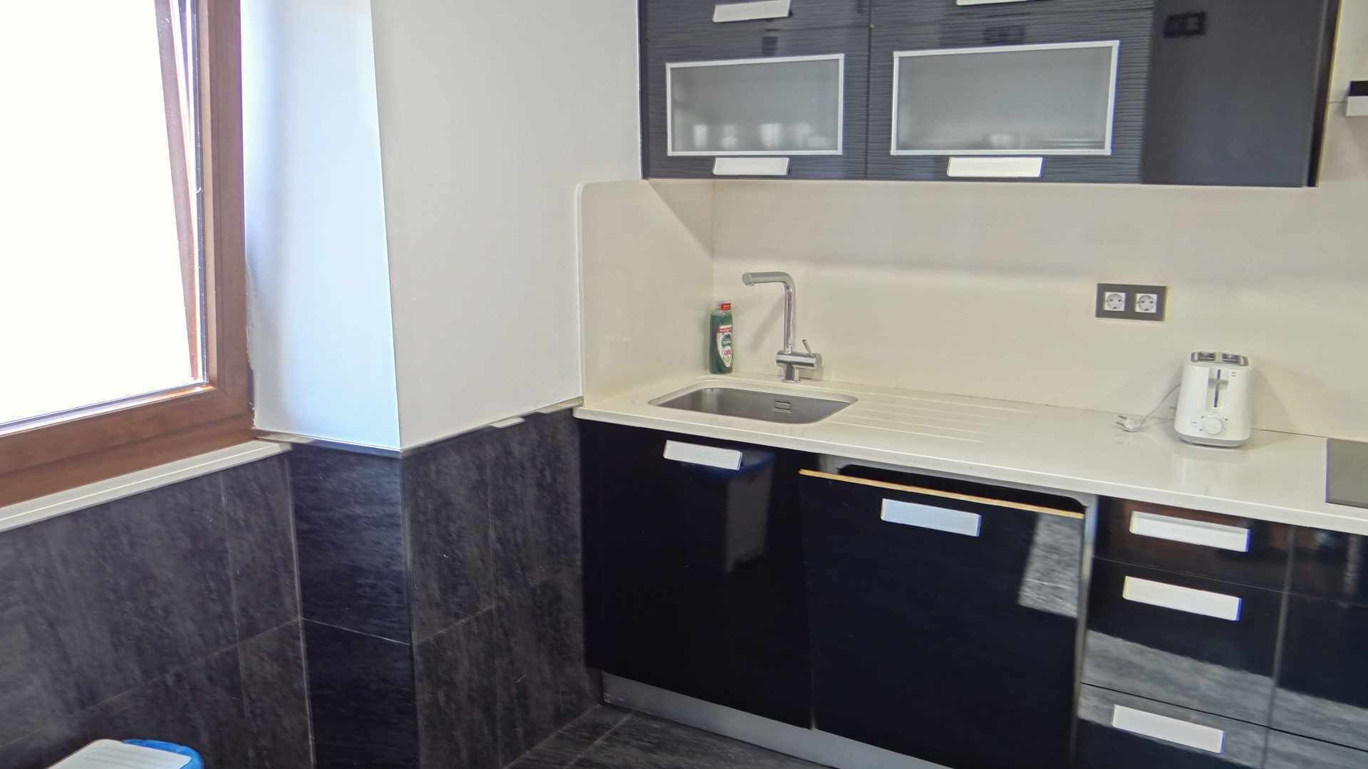 A kitchen with a sink, a toaster, and cabinets.