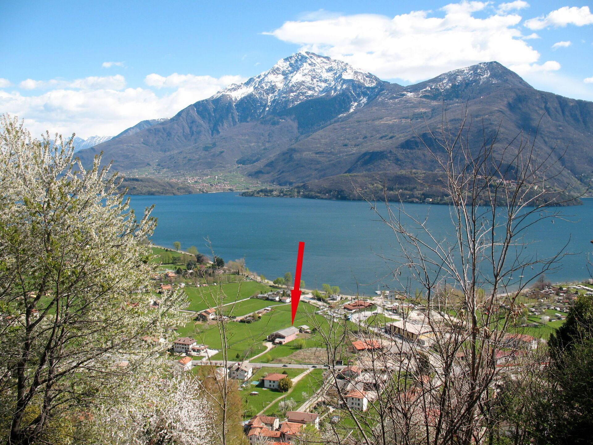 A mountainous landscape with a lake, a village, and a red flag.