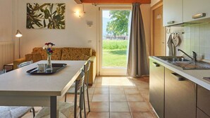 A modern kitchen with a dining area, a sofa, and a view of the outdoors.