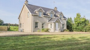 A two-story house with a symmetrical facade, a central entrance, and a chimney. - Craiglea Cottage (Coleraine)