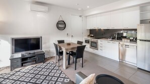 A modern apartment with a dining area, kitchen, and a flat-screen TV. - Bellerive Quay - 2 Bedroom Apartment (Bellerive)