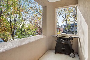 A balcony with a stationary exercise bike, a view of autumn trees, and a building in the background. - Cherrybombe 1920s Art Deco Armadale Apartment (Armadale)