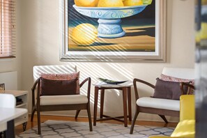 A room with two chairs, a small table, and a painting of fruit on the wall. - Cherrybombe 1920s Art Deco Armadale Apartment (Armadale)