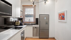 Une cuisine moderne équipée d’appareils électroménagers en acier inoxydable, d’un four encastré et d’un réfrigérateur.